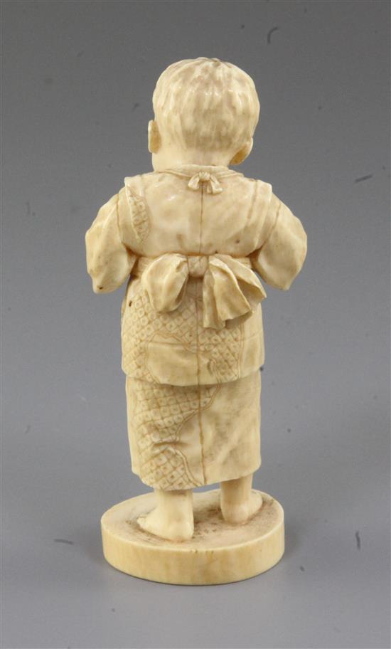 A Japanese ivory okimono of a boy holding a fruit, Tokyo School, Meiji period, 11.5cm